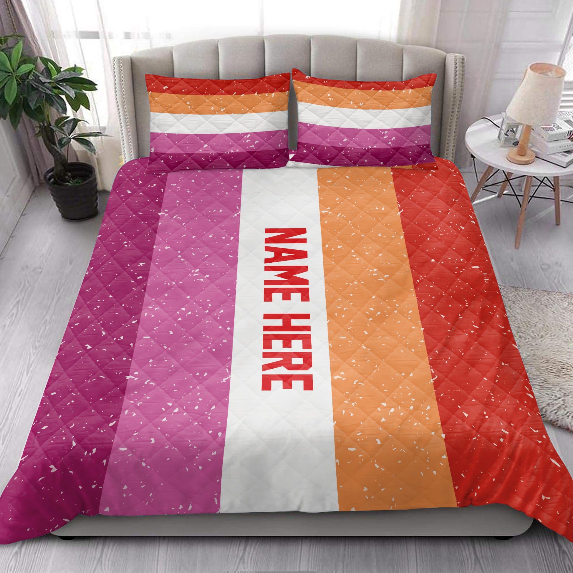 Lesbian pride quilt blanket styled across a modern bed with colorful pink, white, orange, and red stripes