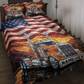 Trucker quilt blanket displayed on a bed with orange semi trucks, mountain sunset scenery, and American flag artwork