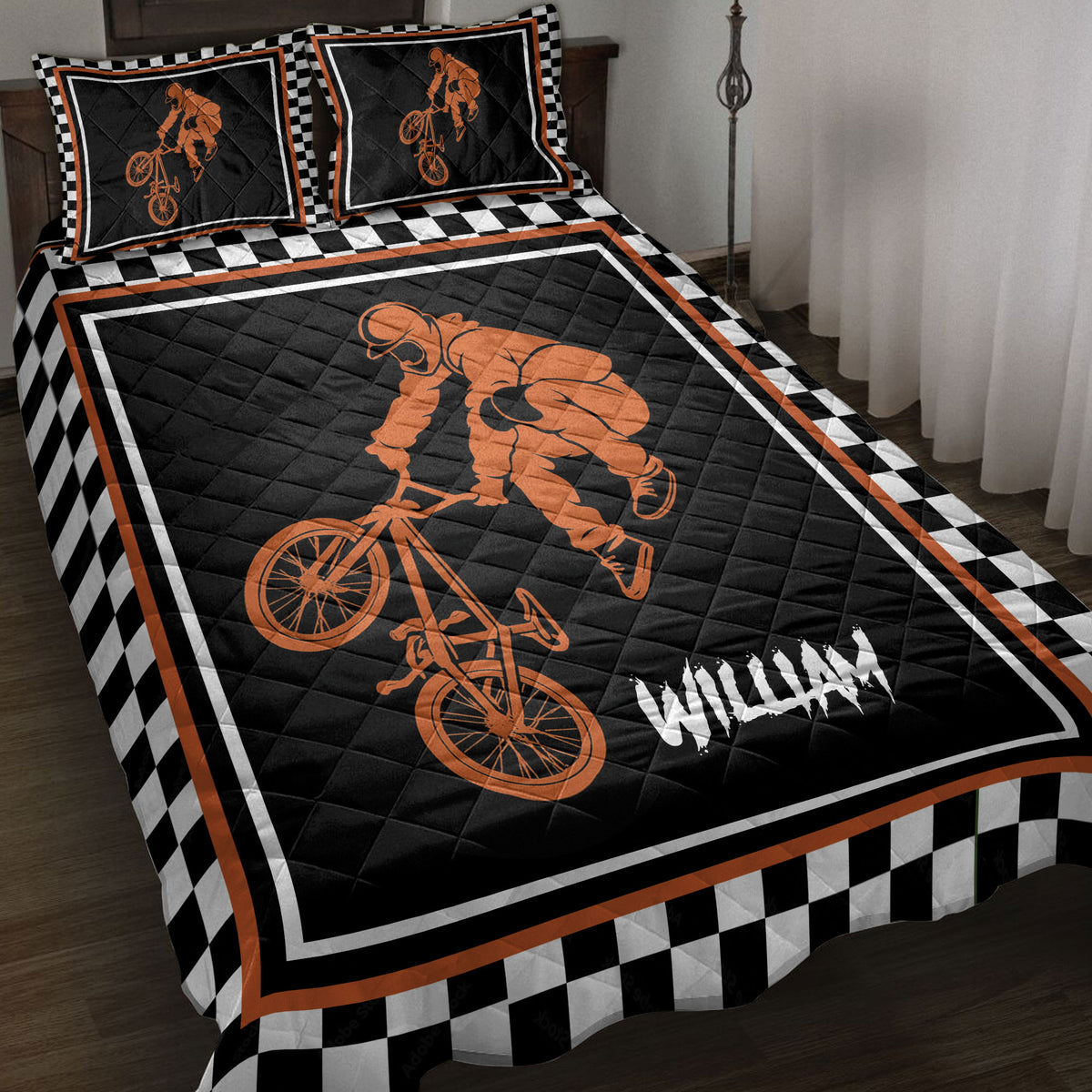 BMX quilt blanket on a bed with orange freestyle rider artwork and black and white checkerboard border