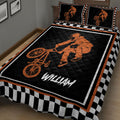 Close bedroom view of BMX quilt blanket with orange bicycle rider artwork and checkerboard border