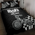 Black BMX quilt blanket displayed on a bed with checkerboard graphics and bicycle artwork