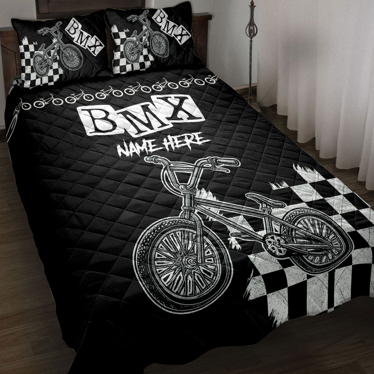 Black BMX quilt blanket displayed on a bed with checkerboard graphics and bicycle artwork