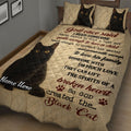Angled bedroom view of a black cat quilt blanket with expressive cat portraits and sentimental artwork