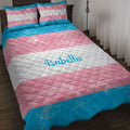 Transgender pride flag quilt blanket displayed on a bed with coordinating striped pillowcases