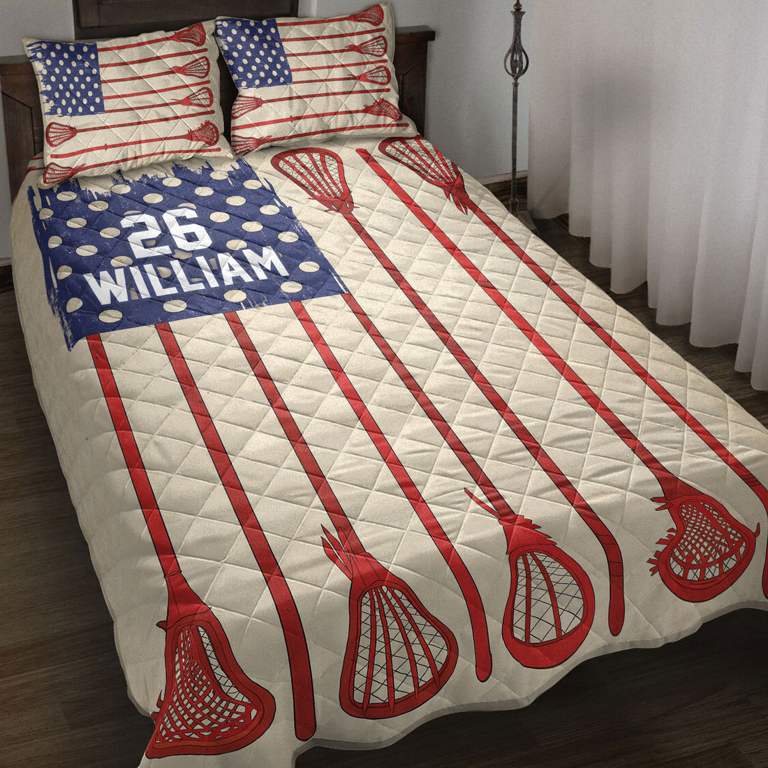Lacrosse quilt blanket spread across a bed with red sticks, cream quilting, and patriotic blue artwork