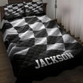 Black and white checkered racing quilt blanket styled on a bed in a dark wood bedroom