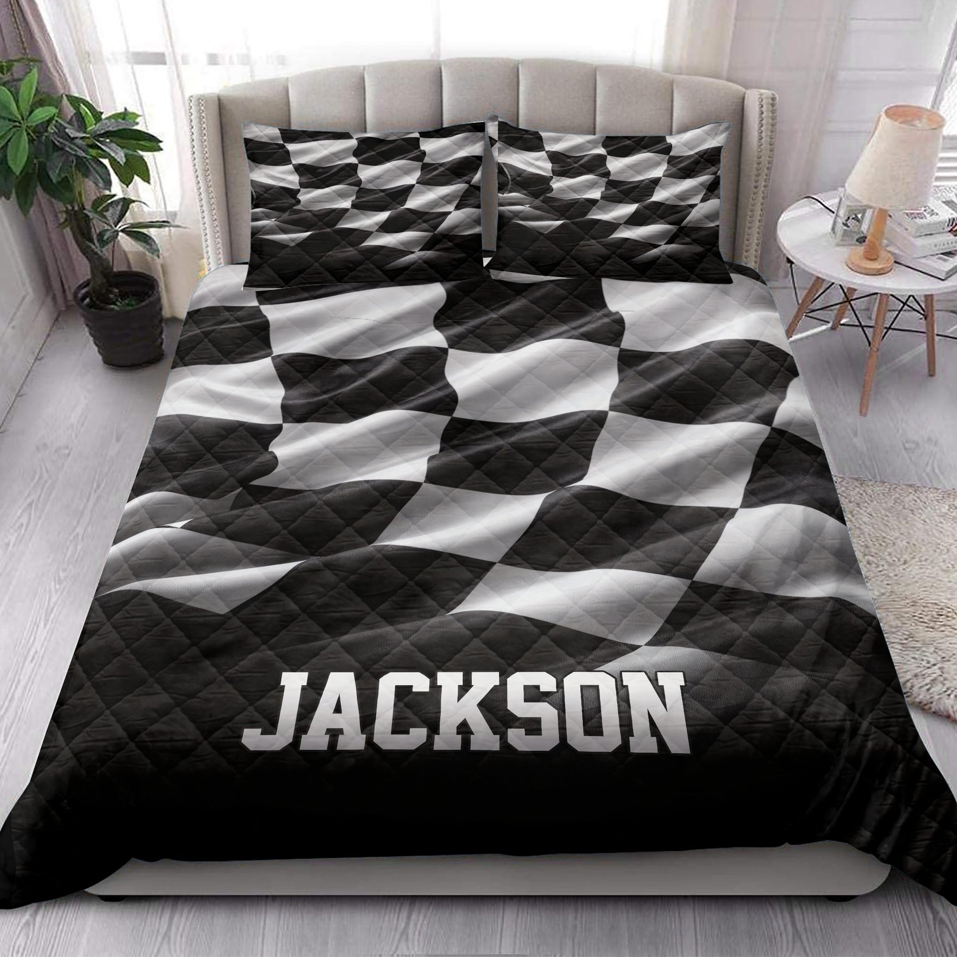 Black and white racing quilt blanket styled across a modern bedroom with matching patterned pillows