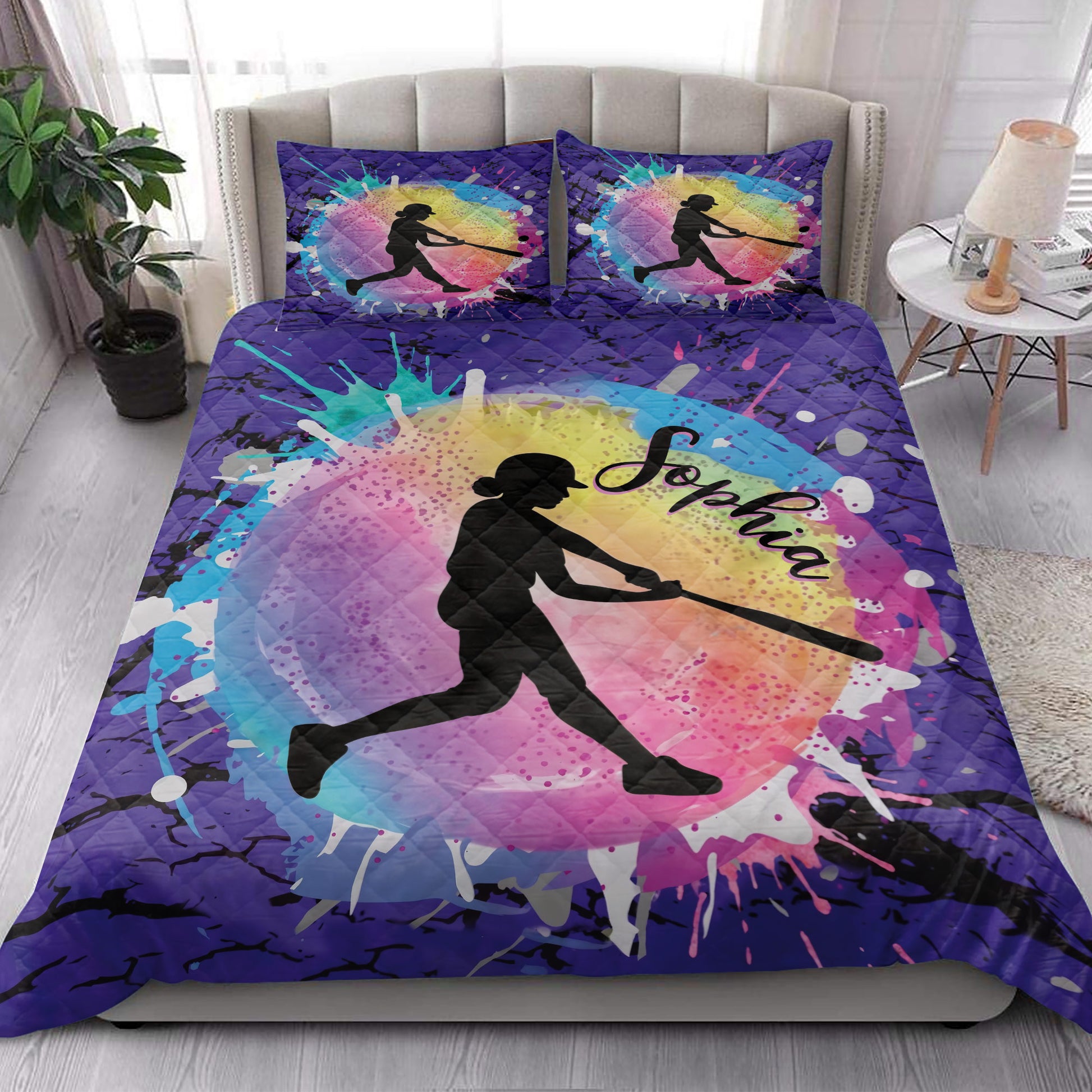 Colorful softball quilt bedding styled on a bedroom bed with batter silhouette artwork
