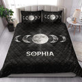 Celestial Wicca quilt blanket styled on a bed with moon phases and starry black artwork