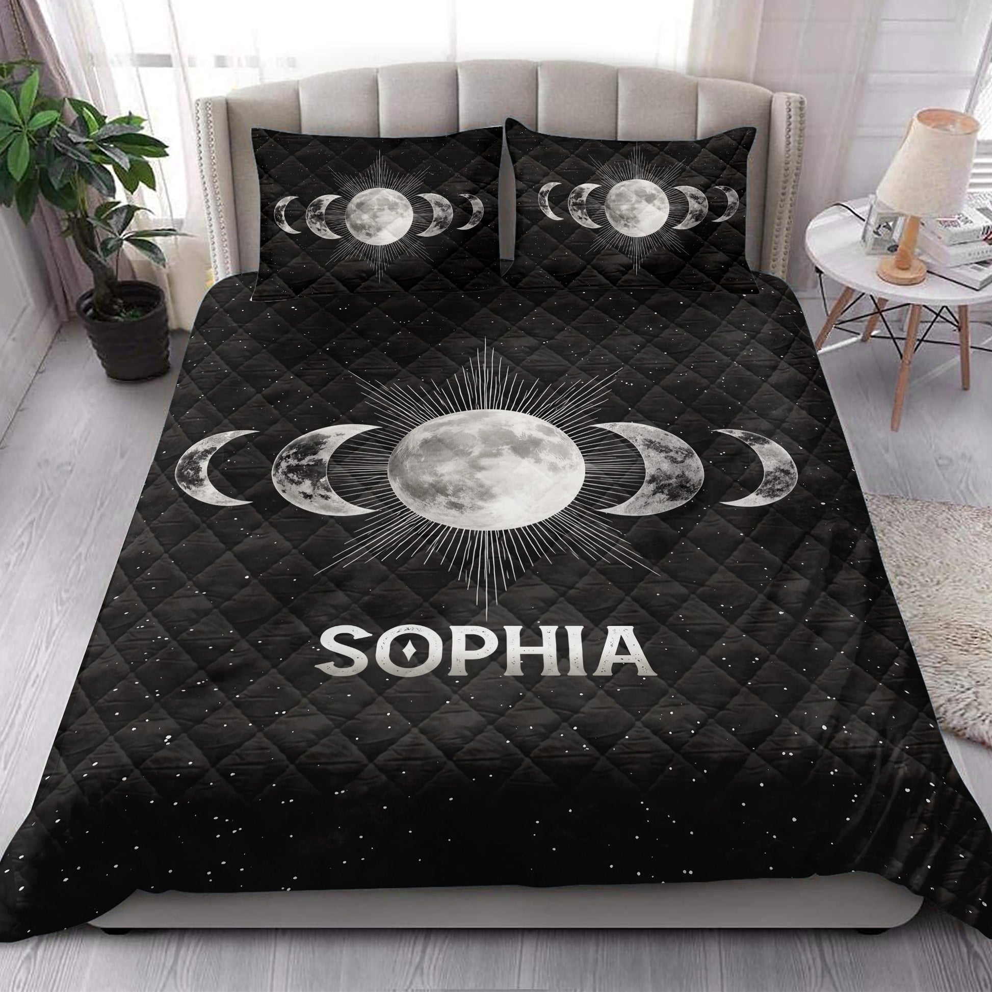 Celestial Wicca quilt blanket styled on a bed with moon phases and starry black artwork