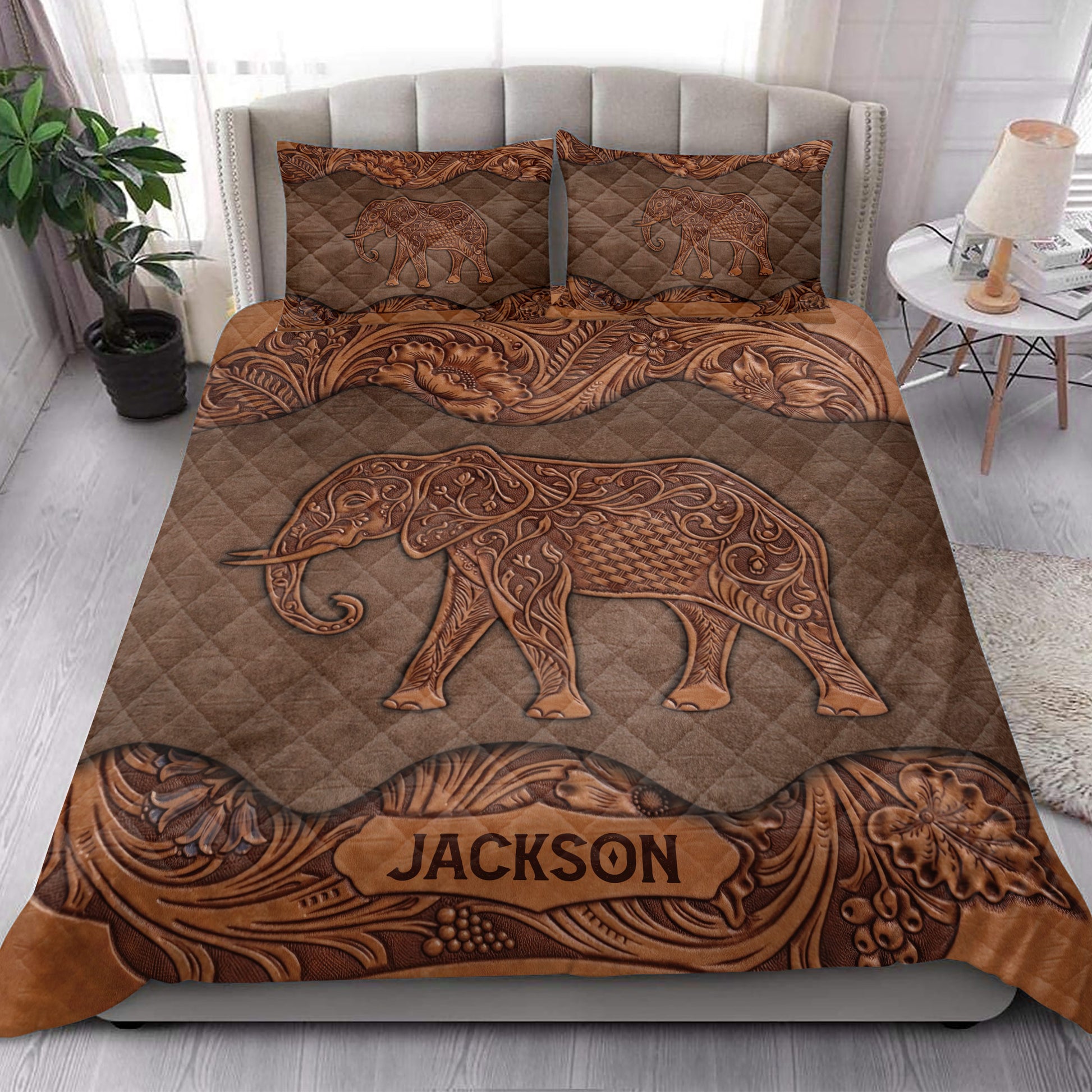 Bedroom display of a brown elephant quilt blanket with ornate floral borders and elephant pillowcases