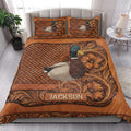 Mallard duck quilt bedding displayed on a bedroom bed with rustic floral borders and copper-brown artwork