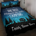 Camping quilt blanket displayed on a bed with pine trees, camper trailer, campfire, and starry night artwork