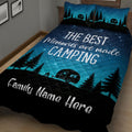 Angled bedroom view of a blue camping quilt with forest, camper trailer, campfire, and night sky artwork