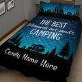 Angled bedroom view of a camping quilt blanket with camper, pine forest, campfire, and starry night artwork