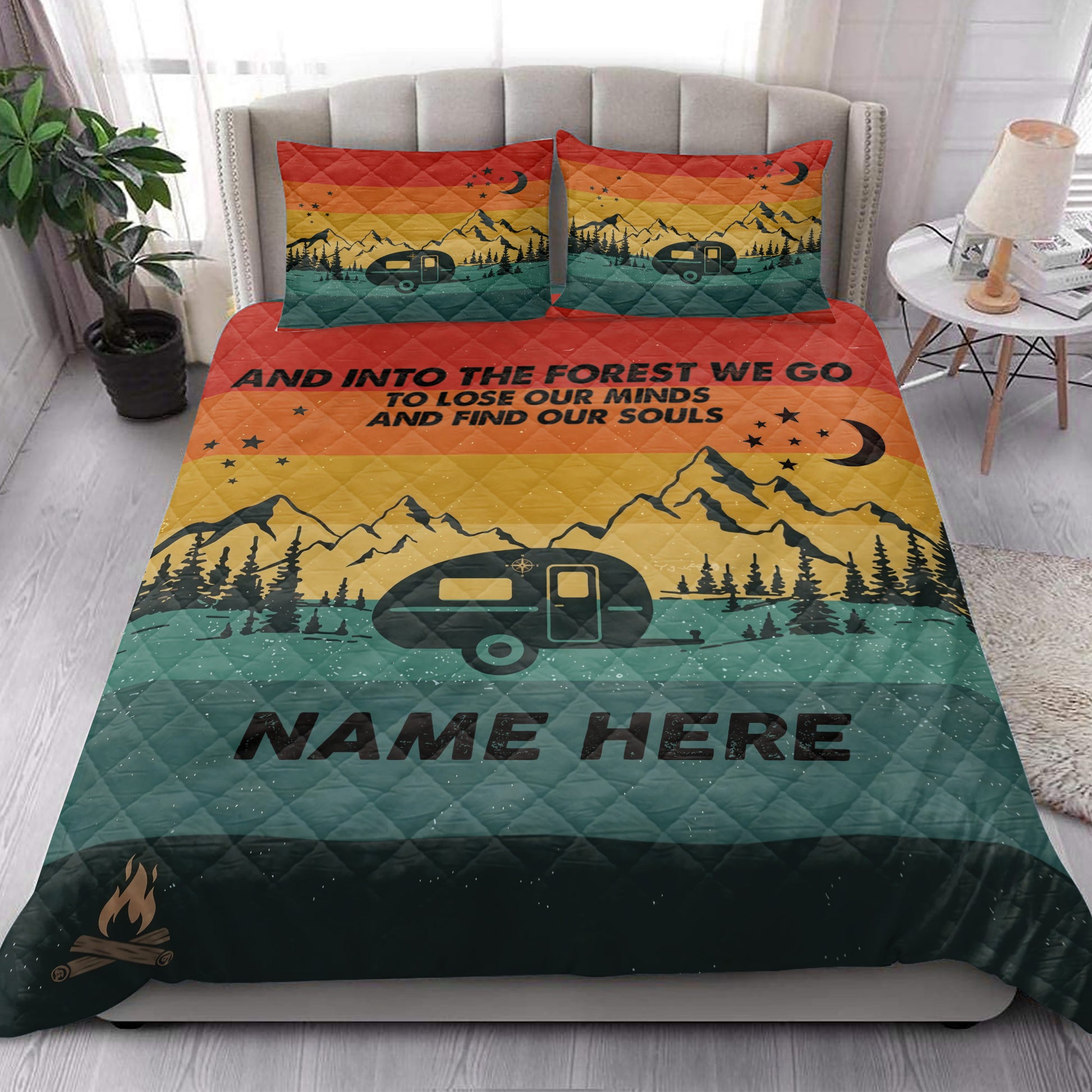 Camping quilt blanket styled on a bedroom bed with travel trailer, mountain, forest, moon, and star artwork