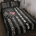Black racing quilt blanket displayed on a bed with checkered flags, tire tracks, stars, and patriotic artwork
