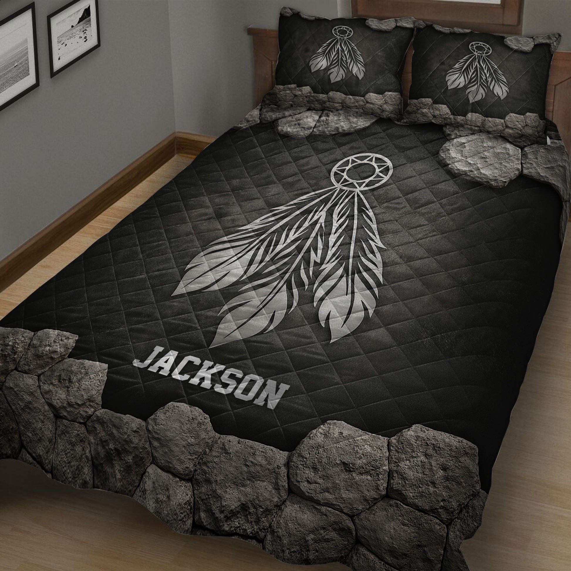 Close bedroom view of a black quilt blanket with large white dreamcatcher and feather artwork