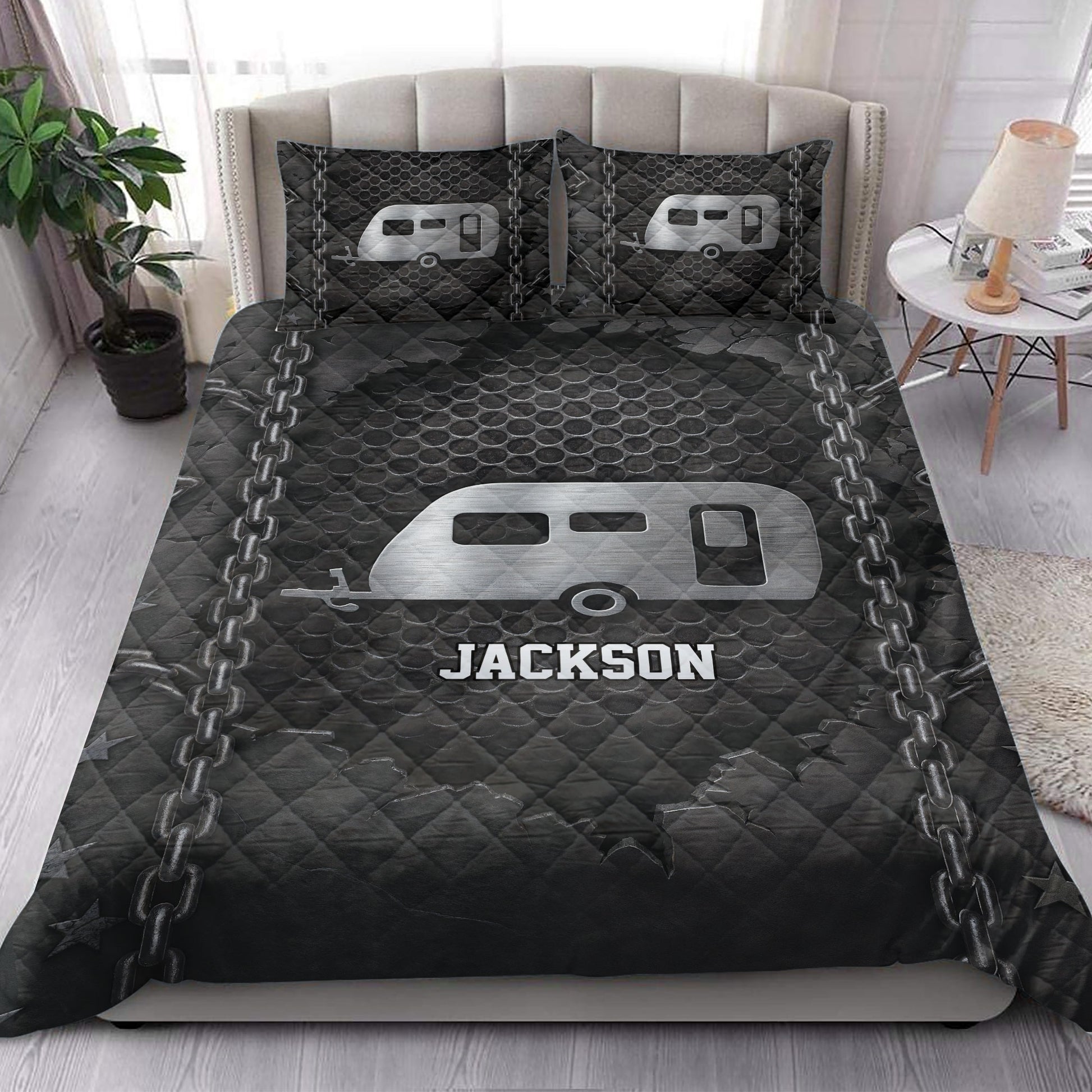 Camping quilt bedding styled on a bed with dark travel trailer and chain artwork