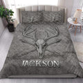 Rustic bedroom styled with a gray hunting quilt blanket featuring deer skull and antler artwork