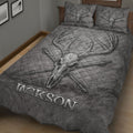 Angled bedroom view of a gray hunting quilt with deer skull, antlers, and crossed arrows