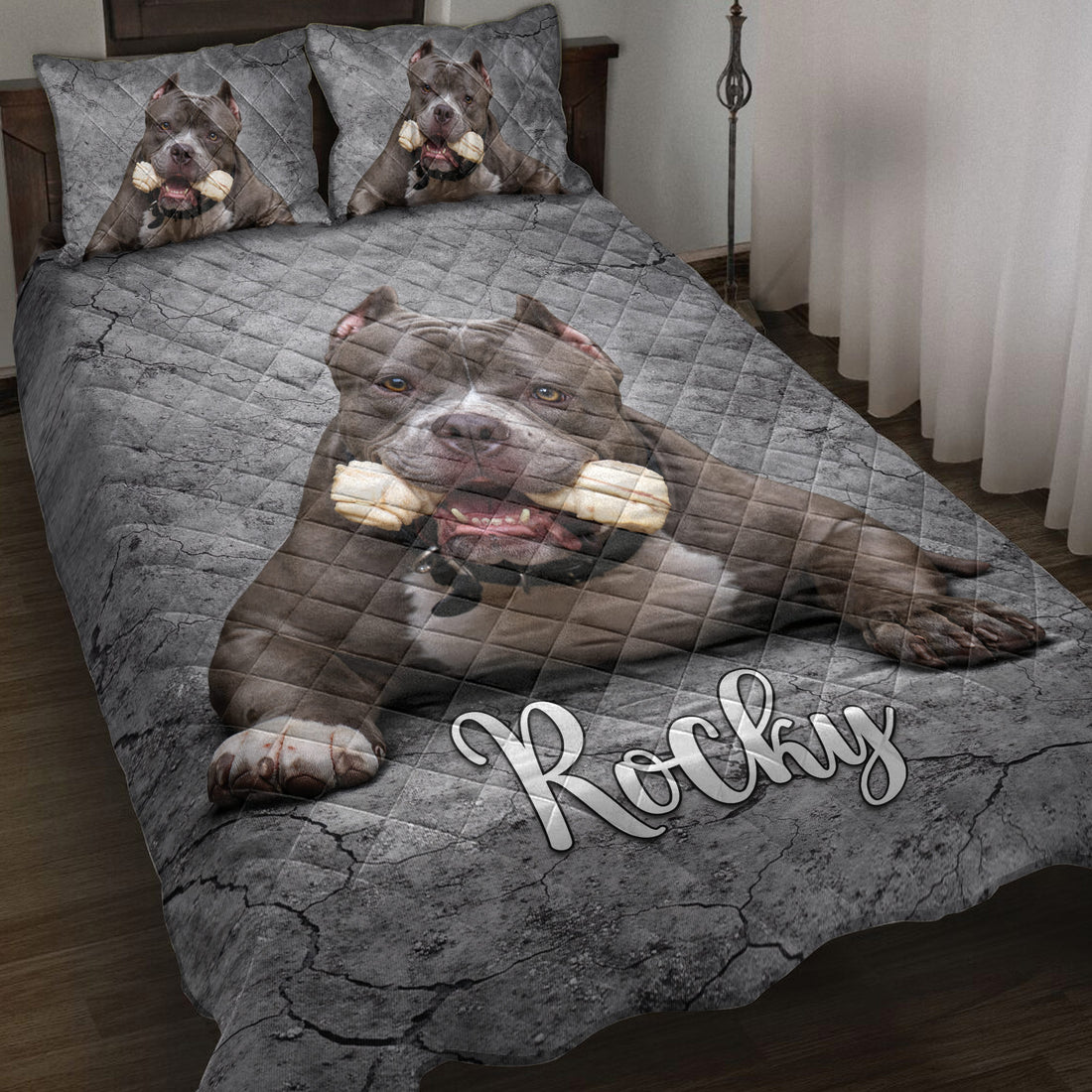 Pitbull quilt blanket displayed on a bed with gray cracked-stone artwork and matching dog portrait details