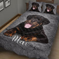Close bedroom view of a Rottweiler quilt blanket with black and tan dog artwork on a gray background