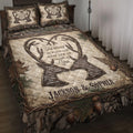 Hunting quilt blanket displayed on a bed with deer antlers, woodland camouflage, pine branches, and rustic rope borders
