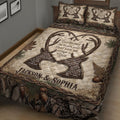 Close bedroom view of a hunting quilt blanket with antler artwork, forest camouflage, oak leaves, and pine details