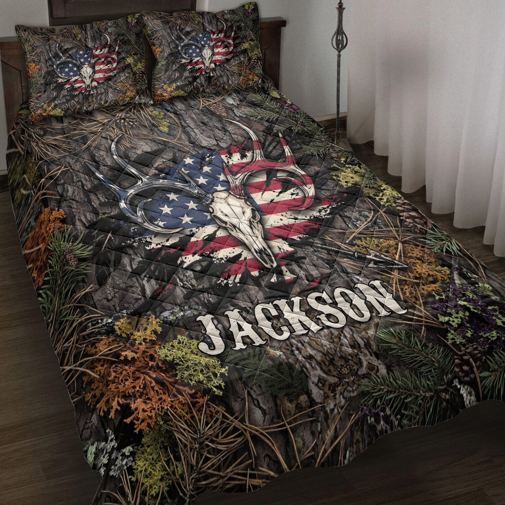 Hunting quilt blanket displayed on a bed with deer skulls, antlers, pine branches, and patriotic woodland artwork