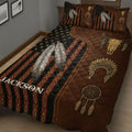 Close view of American Native quilt bedding with white feathers, red geometric bands, dreamcatchers, and bison skulls