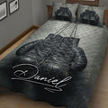 Close bedroom view of a black and gray boxing gloves quilt blanket with gold accents