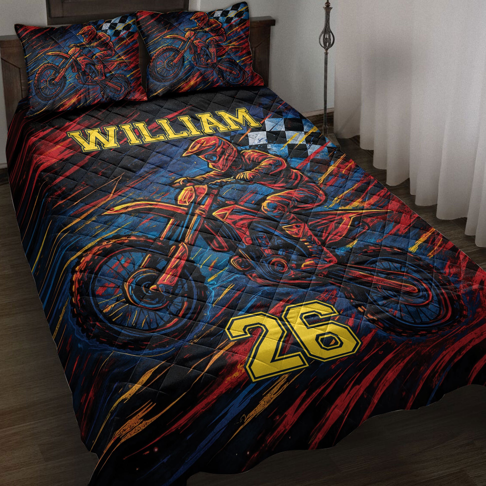 Motocross quilt blanket displayed on a bed with dirt bike rider artwork in red, blue, black, and gold