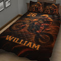 Motocross quilt blanket displayed on a bed with dynamic dirt bike racing artwork in black and orange