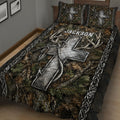Close view of hunting quilt blanket featuring camouflage foliage, large deer antlers, arrows, and dark woodland colors