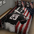 Close bedroom view of a baseball quilt featuring a batter, crossed bat, baseball stitching, and distressed patriotic artwork
