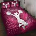 Pink and burgundy cheerleading quilt blanket displayed on a bed with cheerleader silhouettes and pom-poms