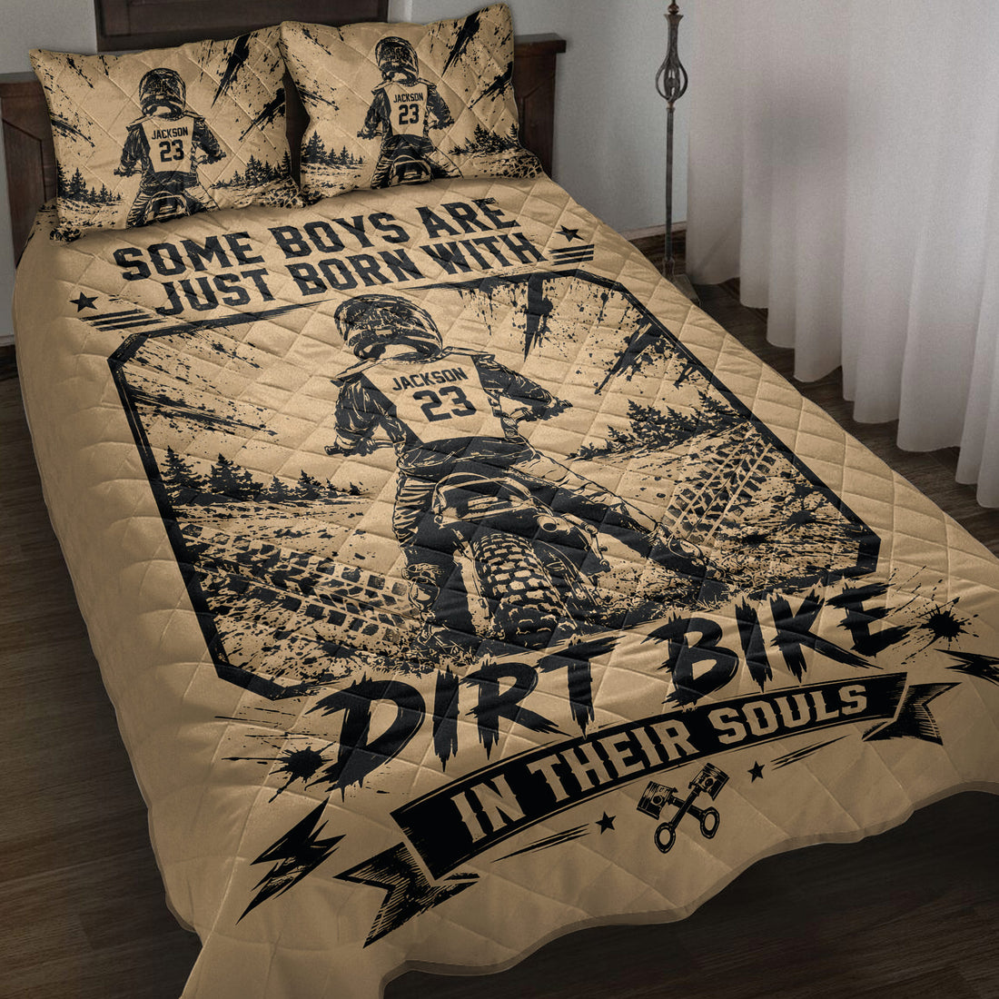 Motocross quilt blanket displayed on a bed with dirt bike rider artwork, tire tracks, trees, and bold black graphics