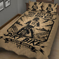Close bedroom view of a motocross quilt blanket featuring a rider on a dirt bike, tire marks, trees, and bold graphics