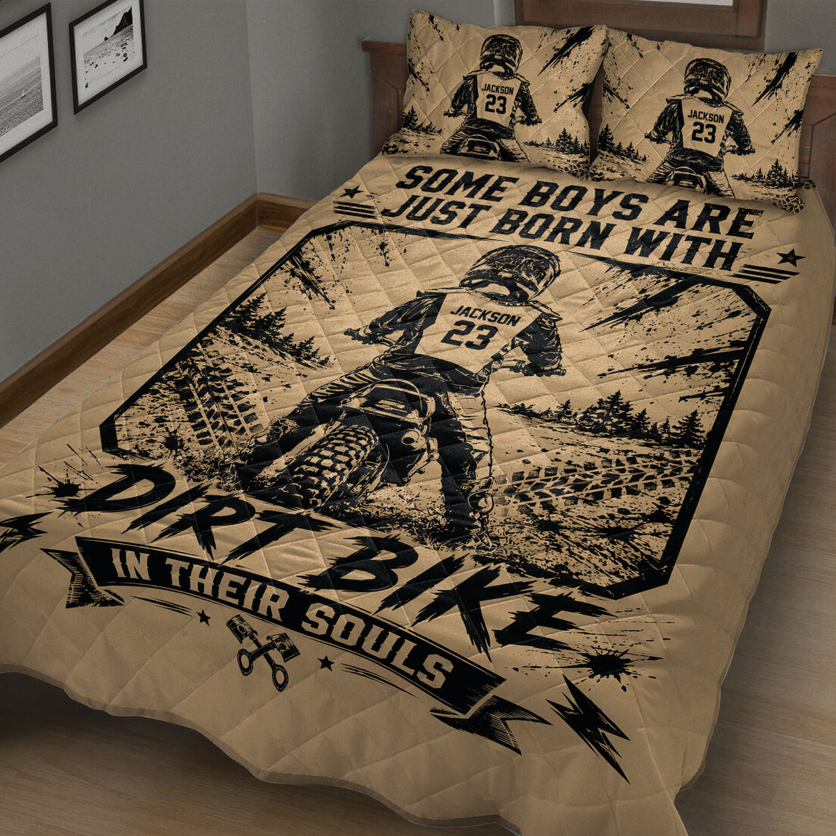 Close bedroom view of a motocross quilt blanket featuring a rider on a dirt bike, tire marks, trees, and bold graphics