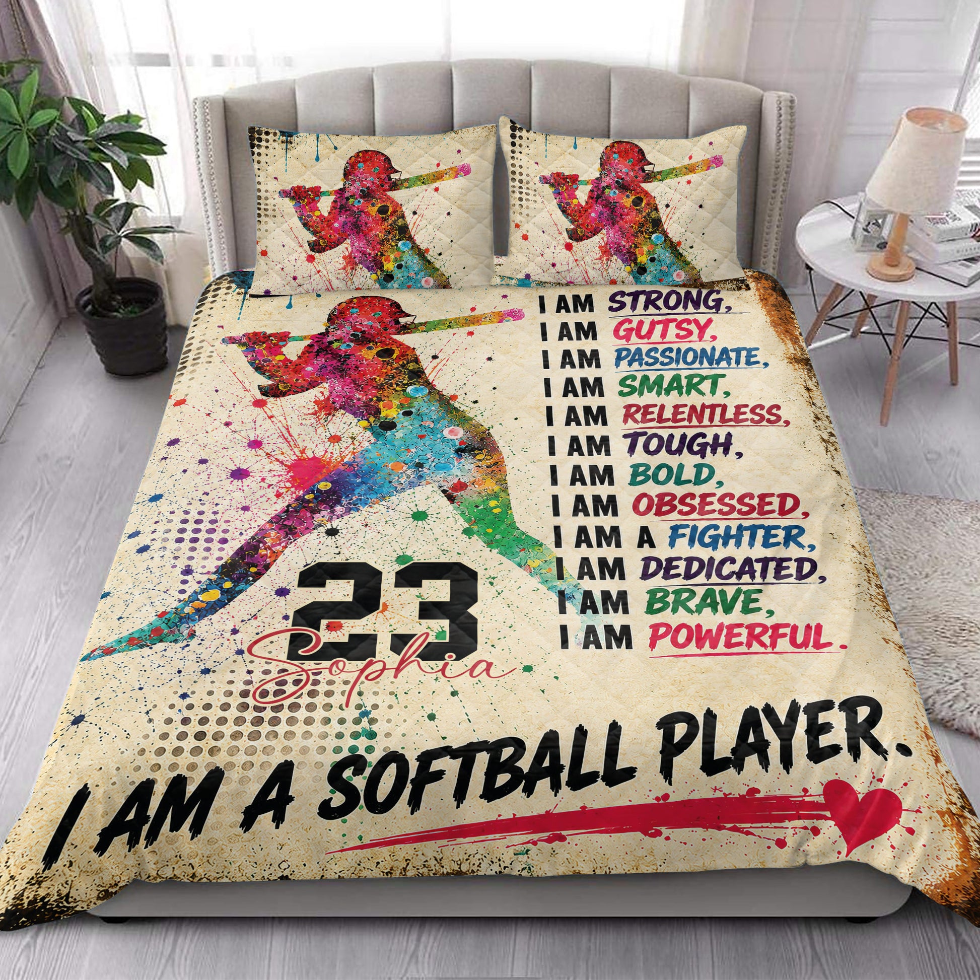 Softball player quilt bedding styled on a bright bedroom bed with colorful motivational artwork