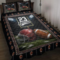 Football quilt blanket bedding set on a bed with stadium lights, helmet, footballs, and field artwork