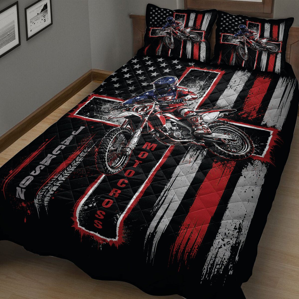 Close bedroom view of a black motocross quilt with red and white stripes, stars, and dirt bike rider artwork