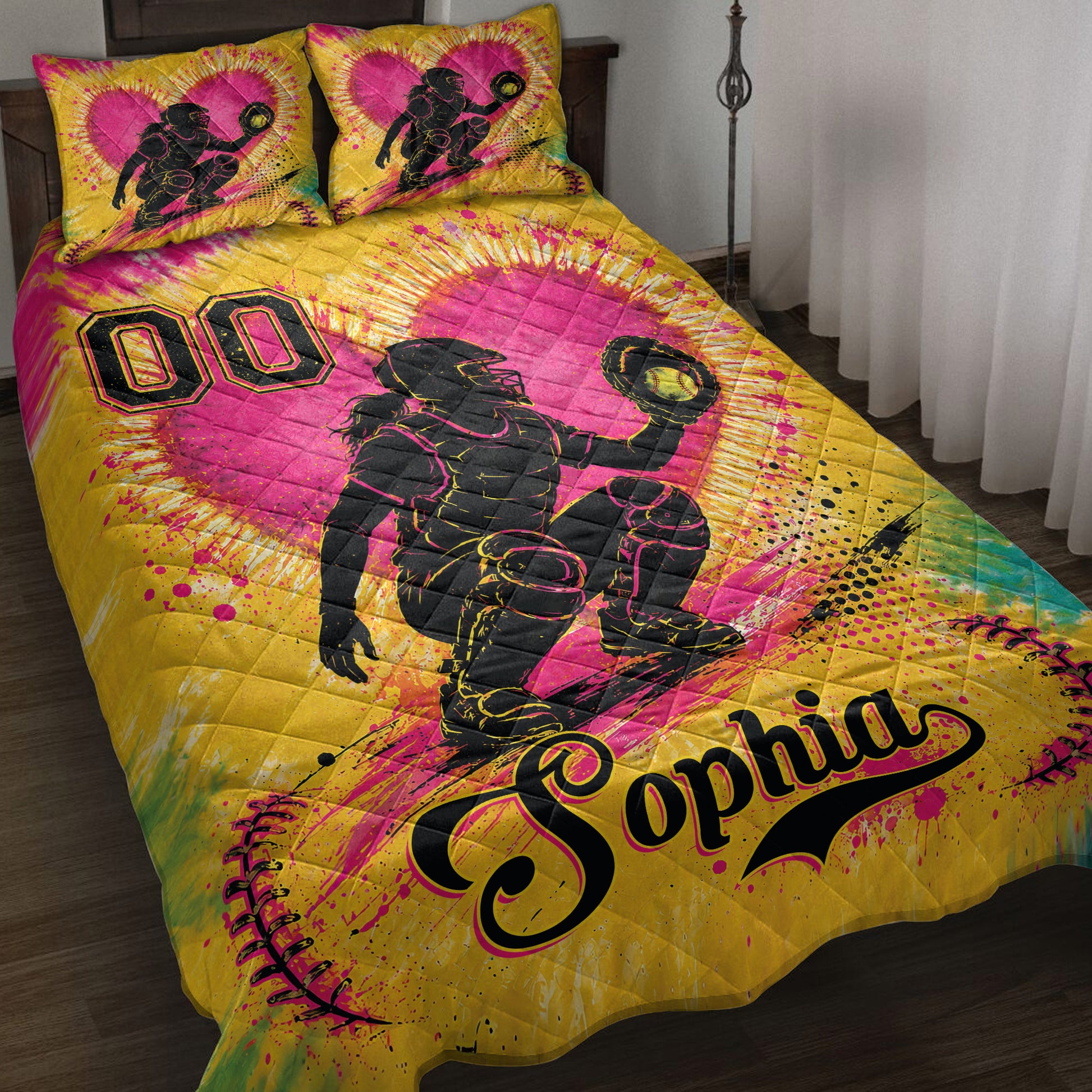 Bright yellow and pink softball quilt blanket displayed on a bed with catcher artwork and softball graphics