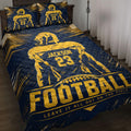 Navy and gold football quilt bedding set displayed on a bedroom bed with player artwork