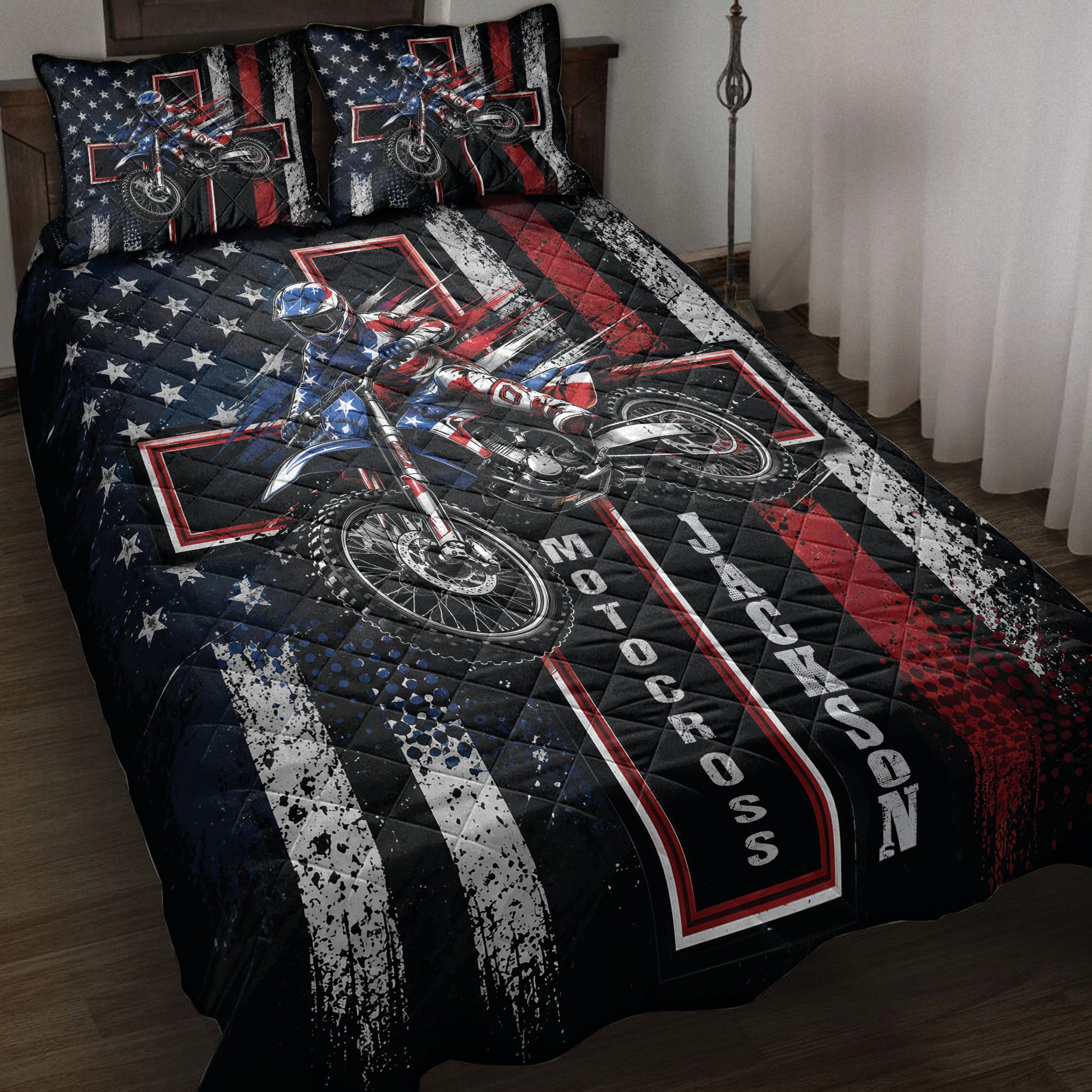 Motocross quilt blanket displayed on a bed with dirt bike rider artwork in black, red, white, and blue