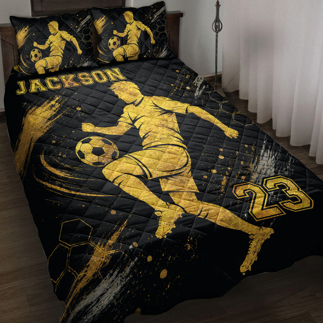 Black and gold soccer quilt blanket displayed on a bed with player silhouettes and soccer ball artwork