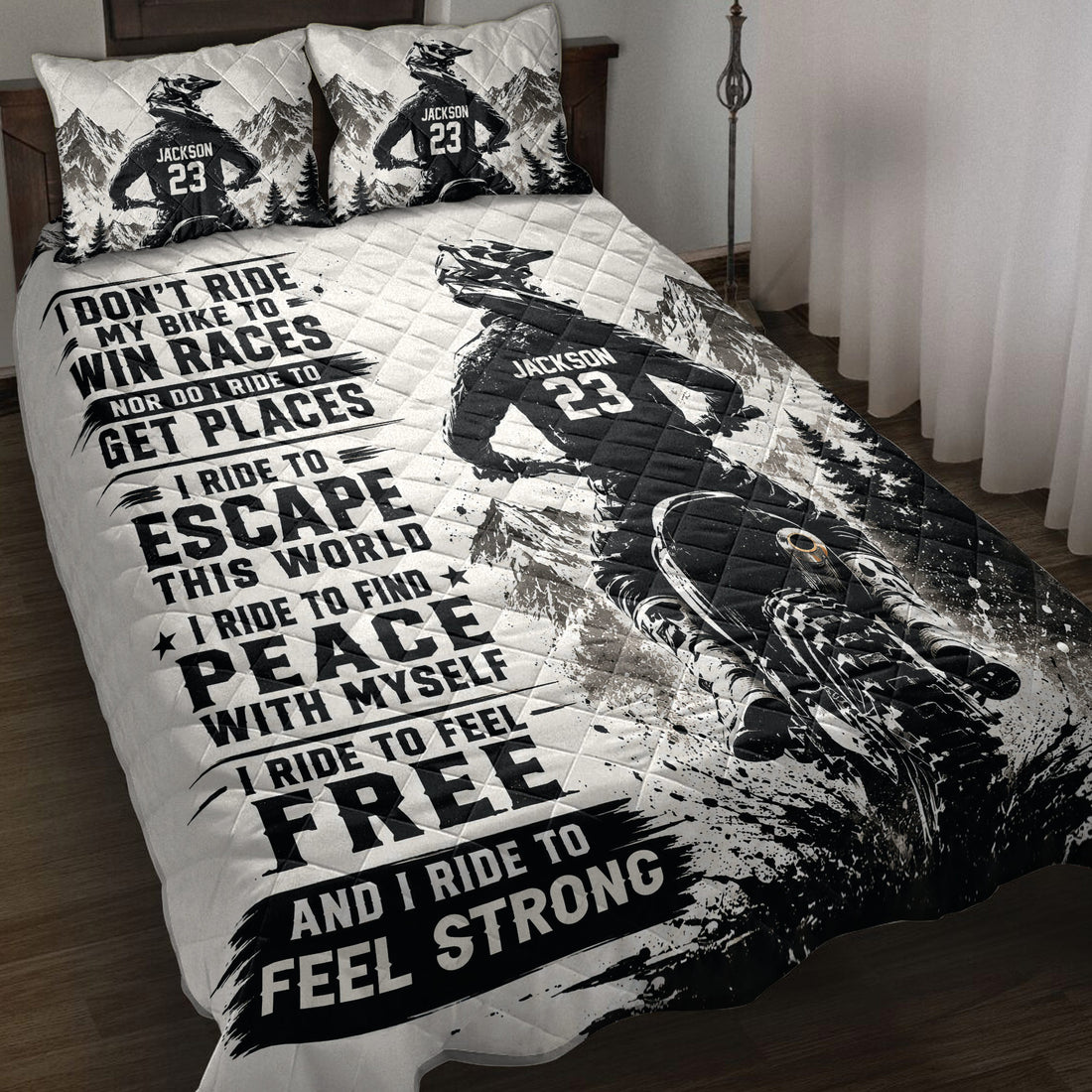 Motocross quilt blanket displayed on a bed with dirt bike rider, mountain scenery, and bold black and white artwork