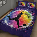 Close bedroom view of a purple soccer quilt with female player silhouette, soccer ball, and rainbow paint-splash design