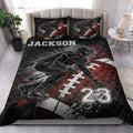 Football quilt blanket styled on a bedroom bed with dramatic black, red, and white artwork